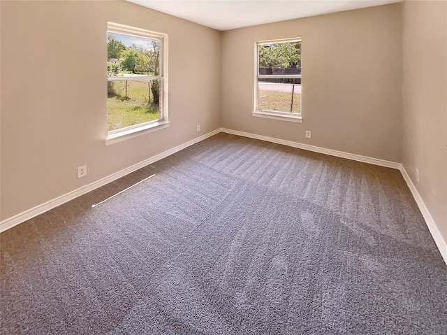 spare room with plenty of natural light and dark carpet