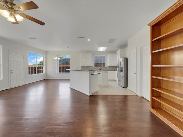 kitchen with light wood-type flooring, a kitchen island, white cabinetry, stainless steel refrigerator with ice dispenser, and ceiling fan with notable chandelier