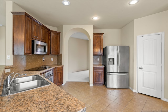 kitchen with light tile flooring, stainless steel appliances, backsplash, light stone countertops, and sink