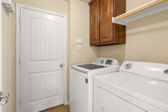 laundry area with tile floors, washer and clothes dryer, and cabinets