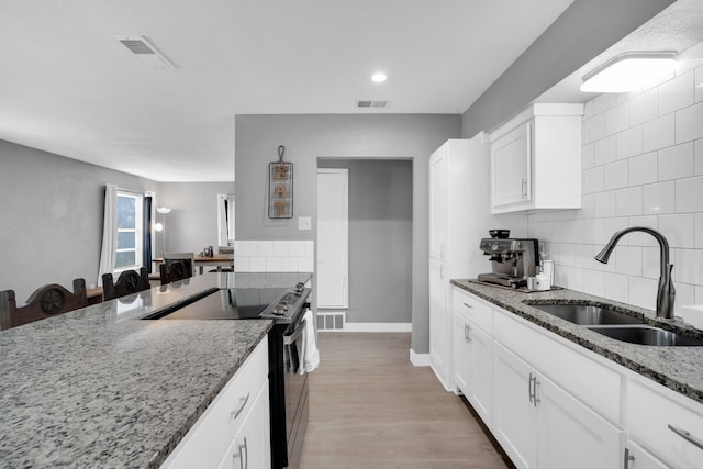 kitchen with stainless steel range with electric cooktop, light hardwood / wood-style flooring, sink, and tasteful backsplash