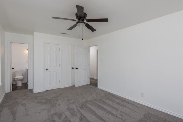 unfurnished bedroom with dark colored carpet, connected bathroom, and ceiling fan