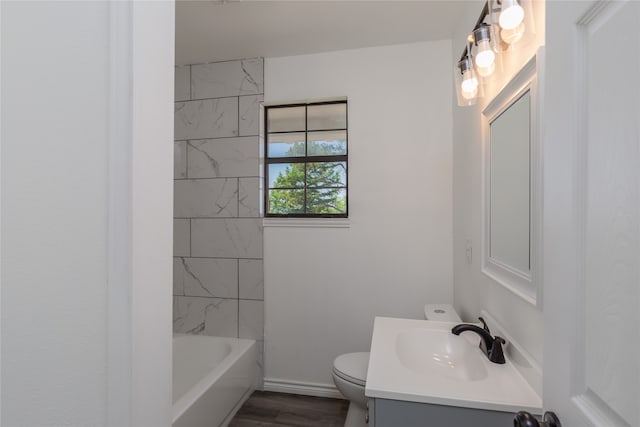 full bathroom with hardwood / wood-style floors, vanity with extensive cabinet space, tiled shower / bath combo, and toilet