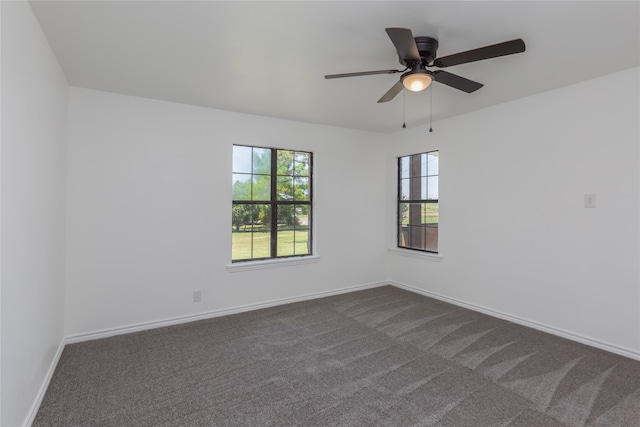 spare room with dark colored carpet and ceiling fan