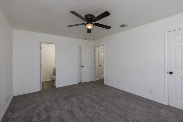 unfurnished bedroom featuring dark colored carpet, ceiling fan, and connected bathroom