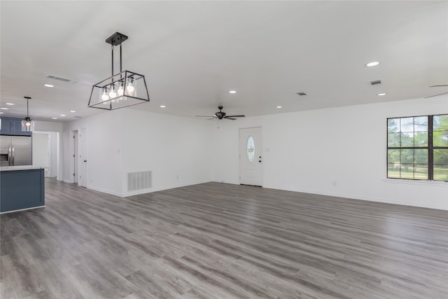 unfurnished room with wood-type flooring and ceiling fan with notable chandelier