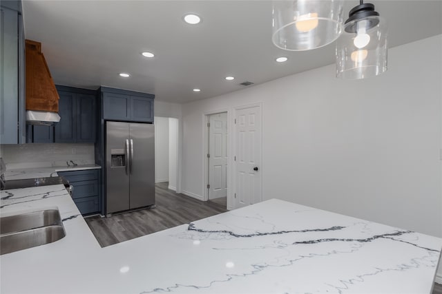 kitchen with backsplash, stainless steel fridge, light stone counters, dark wood-type flooring, and range