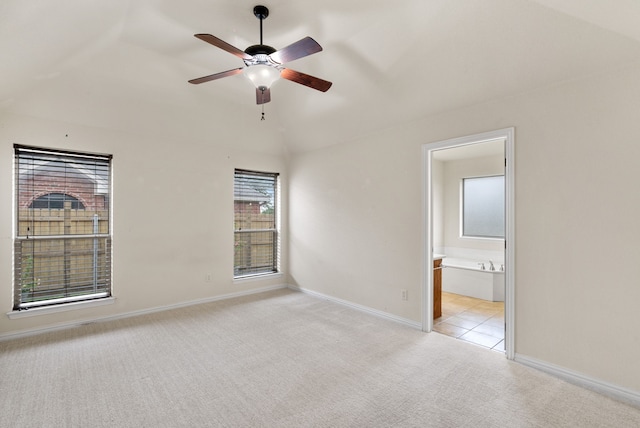 spare room with light carpet, vaulted ceiling, and ceiling fan