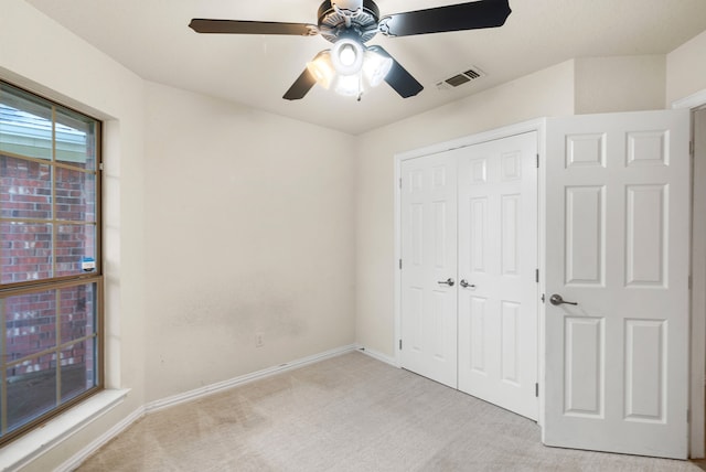 unfurnished bedroom featuring light carpet, a closet, and ceiling fan