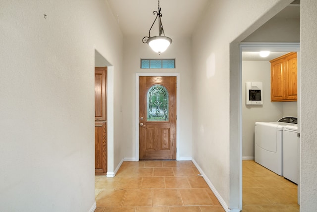 tiled foyer entrance with separate washer and dryer