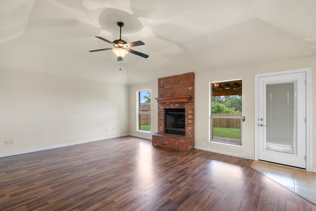 unfurnished living room featuring wood-type flooring, a fireplace, brick wall, ceiling fan, and lofted ceiling