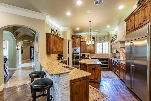 kitchen featuring tasteful backsplash, a center island, pendant lighting, and built in appliances