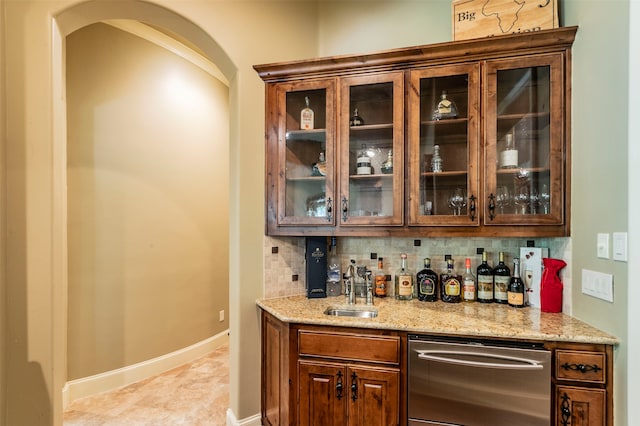 bar featuring light stone countertops, dishwasher, tasteful backsplash, sink, and light tile floors