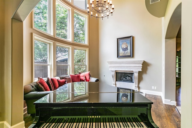 living room featuring hardwood / wood-style flooring, a high end fireplace, a towering ceiling, and a notable chandelier