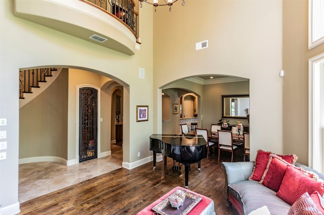 living room featuring ornamental molding, an inviting chandelier, tile floors, and a towering ceiling