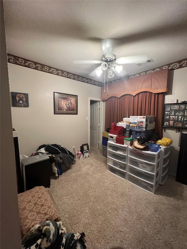 carpeted bedroom with ceiling fan and a textured ceiling