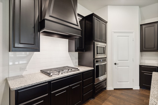 kitchen with appliances with stainless steel finishes, dark wood-type flooring, decorative backsplash, and custom range hood