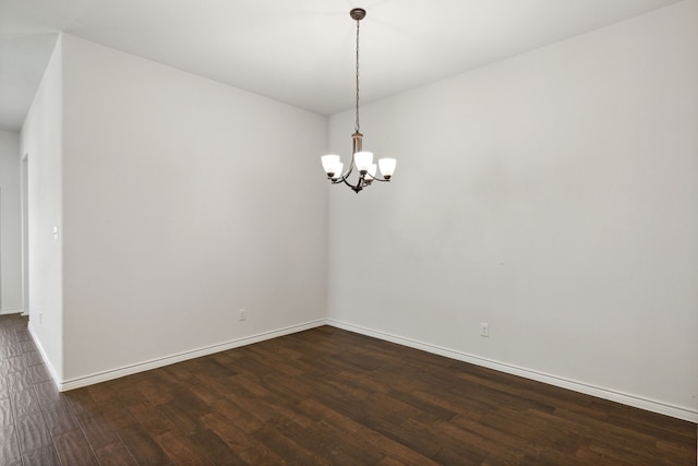 spare room with hardwood / wood-style floors and an inviting chandelier