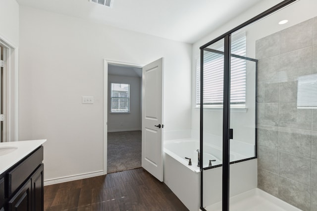 bathroom with a wealth of natural light, hardwood / wood-style flooring, plus walk in shower, and vanity