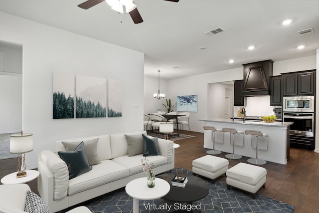 living room with sink, dark wood-type flooring, and ceiling fan with notable chandelier