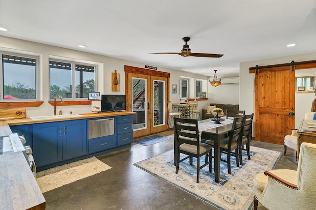 dining area featuring french doors, a barn door, ceiling fan, an AC wall unit, and sink