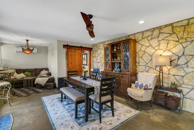 dining area featuring a barn door, ceiling fan, and concrete floors