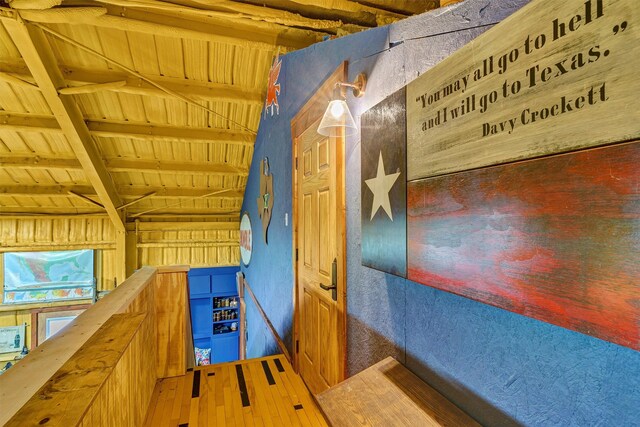 interior space featuring wood-type flooring, wood ceiling, wood walls, and lofted ceiling with beams