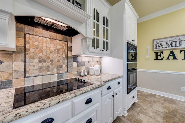 kitchen featuring backsplash, black appliances, light stone countertops, white cabinets, and light tile floors