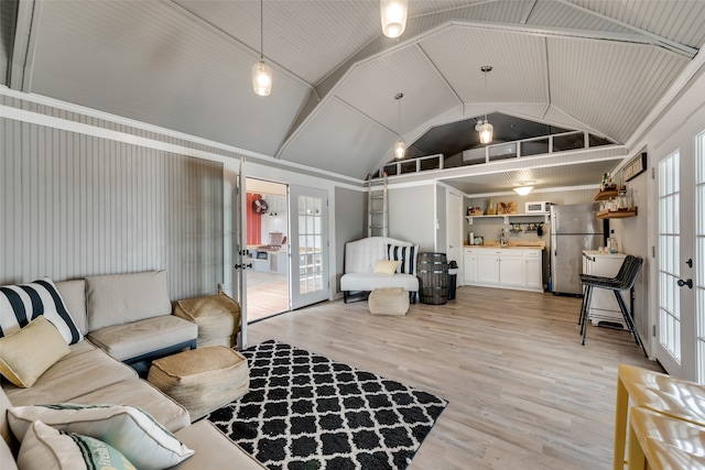 living room featuring light hardwood / wood-style floors, french doors, a wealth of natural light, and vaulted ceiling