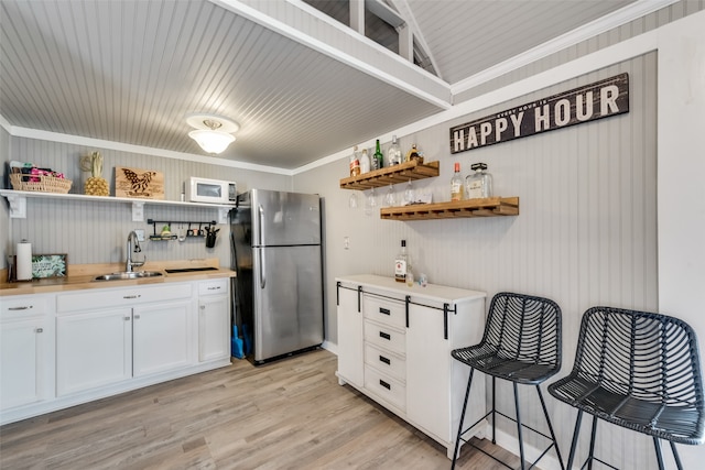 kitchen with ornamental molding, stainless steel fridge, light hardwood / wood-style flooring, white cabinets, and sink