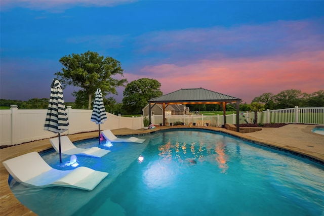 pool at dusk featuring a gazebo