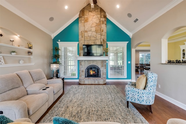 living room with high vaulted ceiling, dark wood-type flooring, a stone fireplace, and crown molding