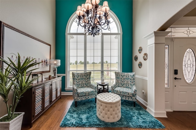 living area featuring a chandelier, hardwood / wood-style flooring, decorative columns, and crown molding