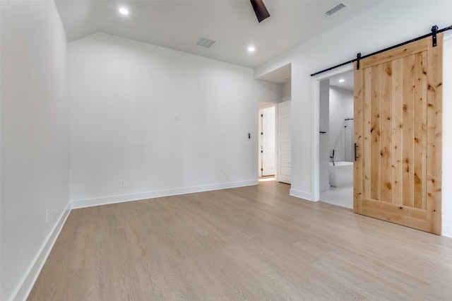 unfurnished room featuring light wood-type flooring and a barn door