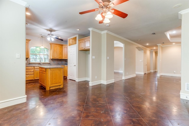 kitchen featuring ceiling fan, tasteful backsplash, decorative light fixtures, a kitchen island, and ornamental molding