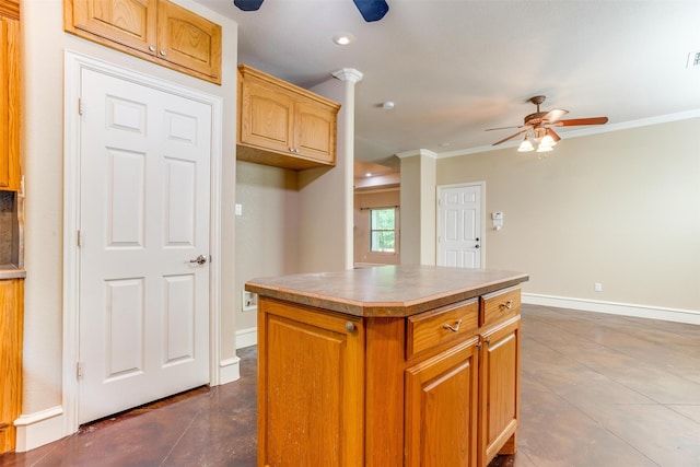 kitchen featuring a center island, dark tile patterned flooring, ceiling fan, and ornamental molding