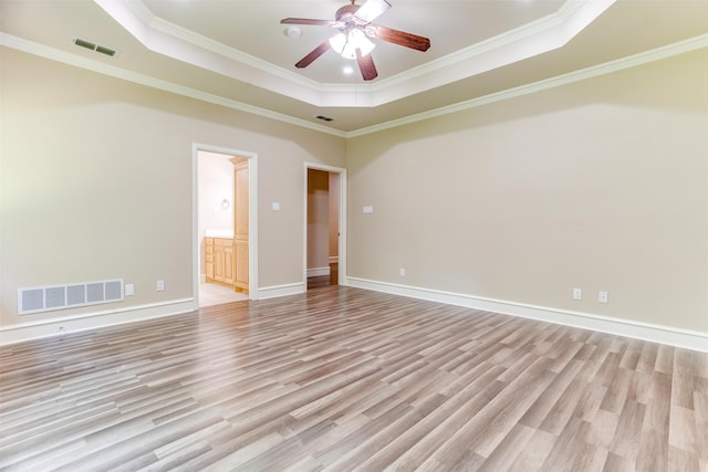 spare room with a tray ceiling, crown molding, ceiling fan, and light hardwood / wood-style floors