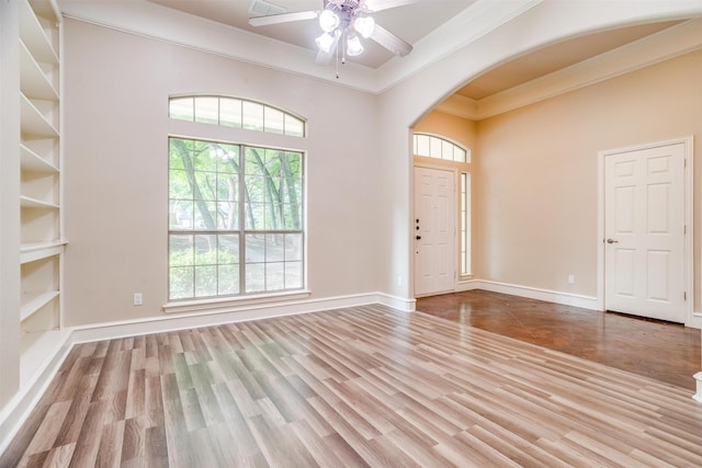 entrance foyer featuring light wood-type flooring, ceiling fan, and crown molding