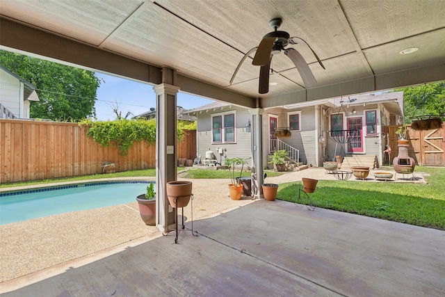 view of patio featuring a fenced in pool, an outdoor fire pit, and ceiling fan