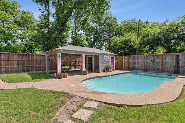 view of pool with a yard and an outbuilding