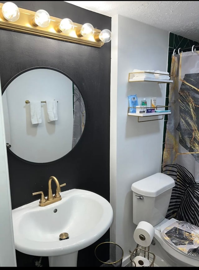 bathroom featuring a textured ceiling, sink, and toilet