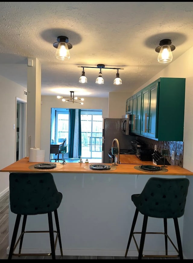 kitchen featuring rail lighting, wood counters, tasteful backsplash, and kitchen peninsula