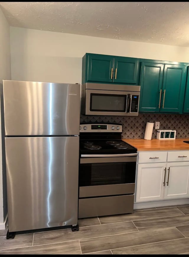 kitchen featuring backsplash, stainless steel appliances, white cabinetry, and wooden counters