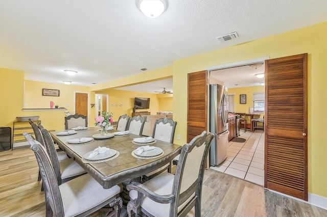 dining room featuring light hardwood / wood-style flooring, ceiling fan, and a textured ceiling