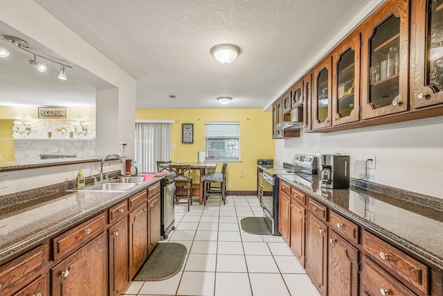 kitchen with stainless steel electric range, light tile floors, a textured ceiling, sink, and rail lighting