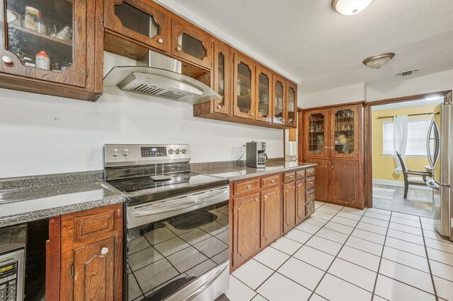 kitchen featuring appliances with stainless steel finishes, a textured ceiling, and light tile floors