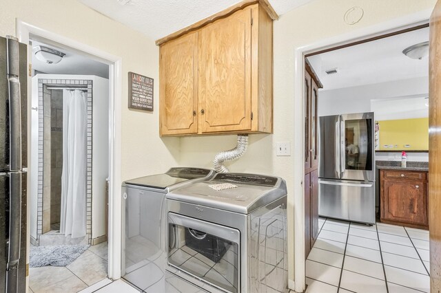 laundry room with cabinets, light tile floors, and washer and clothes dryer