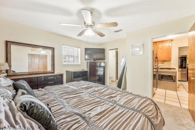 bedroom featuring stainless steel refrigerator, ceiling fan, light tile floors, and ensuite bathroom