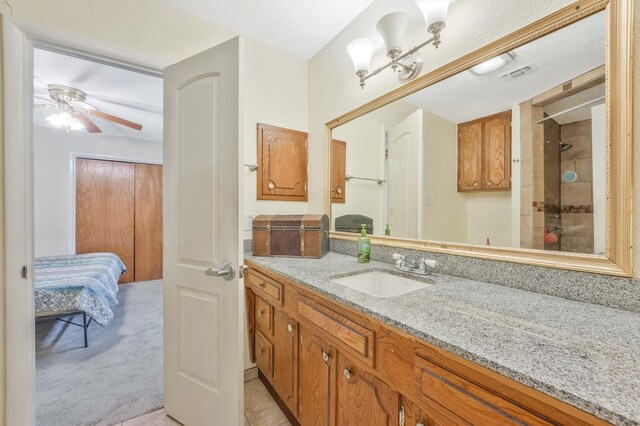 bathroom with walk in shower, ceiling fan, and vanity