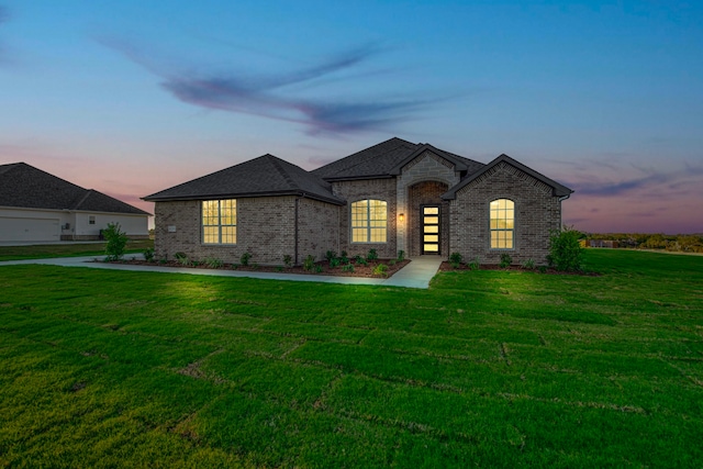 french country inspired facade featuring a yard